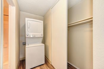 Stackable washer and dryer inside apartment with closet to the right and Hardwood Inspired Floors at Renaissance Park Apartments, Davis, California